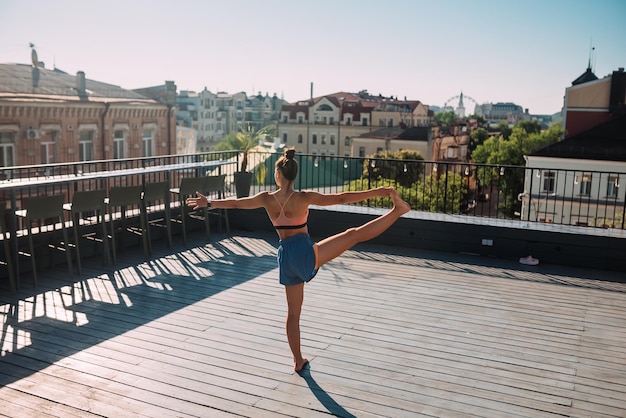 Giovane donna che pratica yoga sul tetto di un edificio