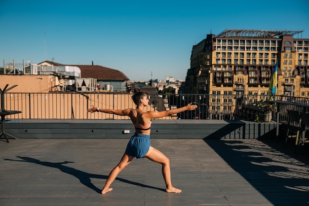 Giovane donna che pratica yoga sul tetto di un edificio