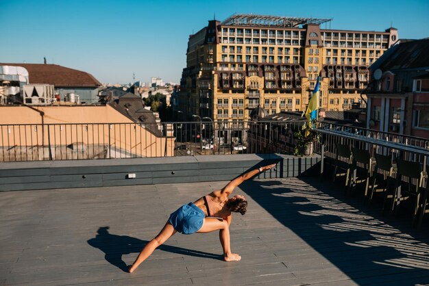 Giovane donna che pratica yoga sul tetto di un edificio