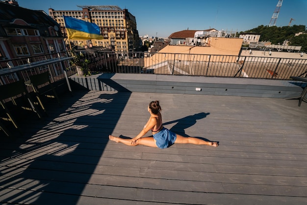 Giovane donna che pratica yoga sul tetto di un edificio