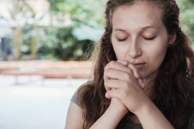 Giovane donna che prega con gli occhi chiusi