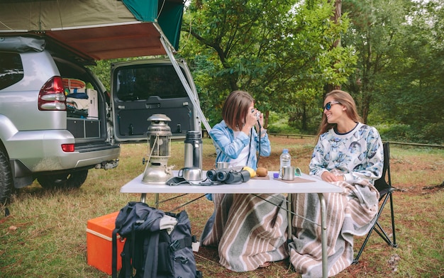 Giovane donna che prende foto ad un amico felice mentre fa colazione in campeggio