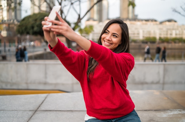 Giovane donna che prende i selfie con il telefono.