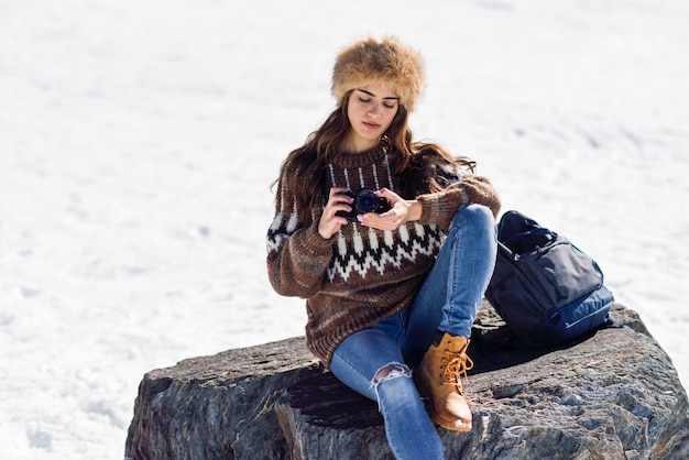 Giovane donna che prende le fotografie nelle montagne nevose