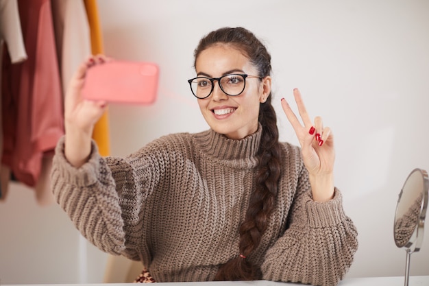 Giovane donna che prende selfie a casa