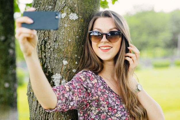 Giovane donna che prende selfie con il telefono al parco