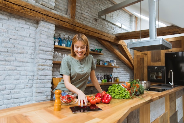 Giovane donna che prepara cibo nella cucina rustica