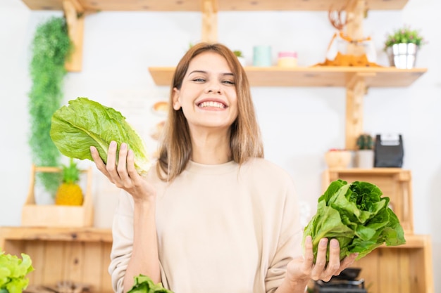 Giovane donna che prepara cibo sano con insalata di verdure donna seduta alla dispensa in una bella cucina interna Il cibo dietetico pulito da prodotti e ingredienti locali Mercato fresco