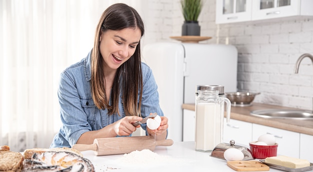 Giovane donna che prepara torte fatte in casa nella spaziosa cucina luminosa si chiuda.