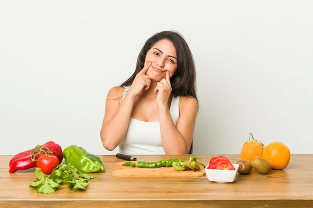 Giovane donna che prepara un pasto sano dubitando tra due opzioni.