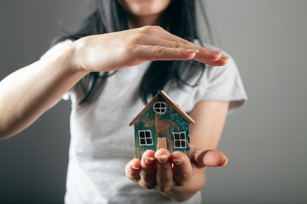 Giovane donna che protegge la casa nelle mani