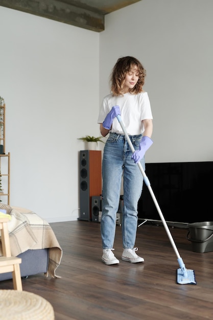Giovane donna che pulisce il pavimento con il mop