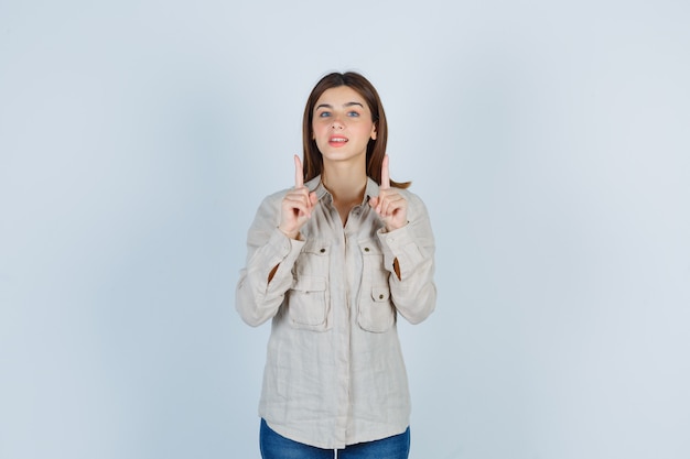 Giovane donna che punta in casual, jeans e sembra soddisfatta, vista frontale.