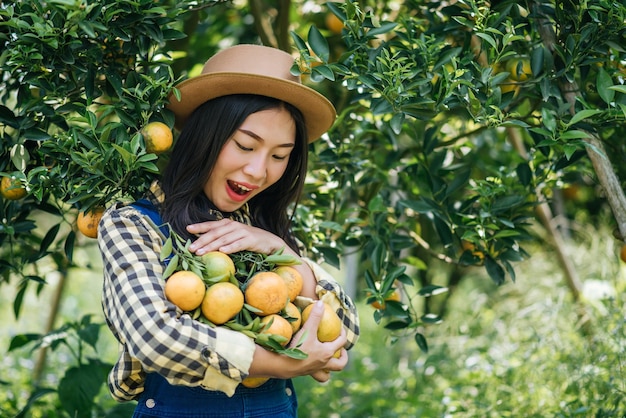 Giovane donna che raccoglie arance nel frutteto