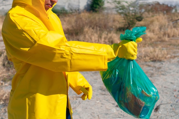 Giovane donna che raccoglie immondizia nella foresta al mattino. Inquinamento ambientale da plastica. Concetto ecologico volontario