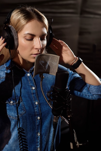 Giovane donna che registra una canzone in studio.