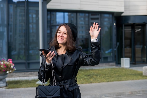 Giovane donna che resta con smartphone e caffè davanti all'ufficio.