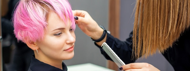 Giovane donna che riceve un taglio di capelli corto rosa