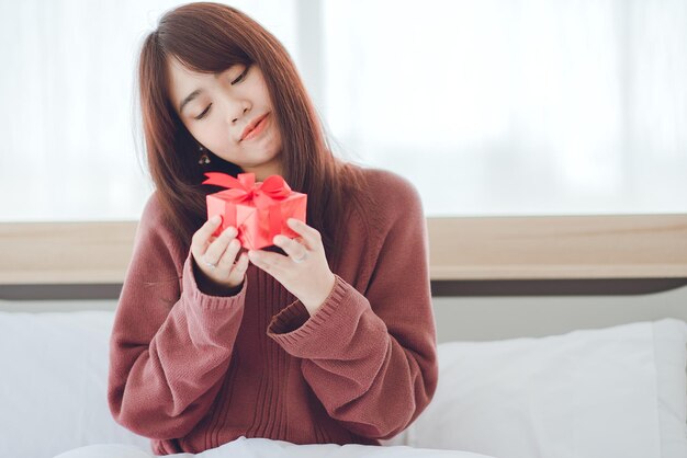 Giovane donna che riceve una confezione regalo a sorpresa dal suo ragazzo a casa