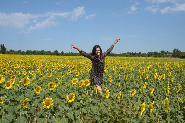 Giovane donna che salta felicemente in un campo di girasole