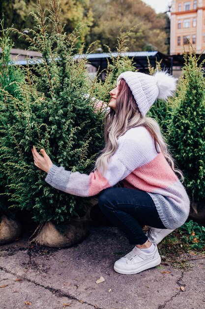 Giovane donna che sceglie un albero di Natale in una serra