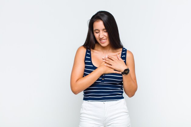 Giovane donna che sembra triste, ferita e affranta, tenendo entrambe le mani vicino al cuore