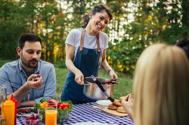 Giovane donna che serve barbecue ai suoi amici