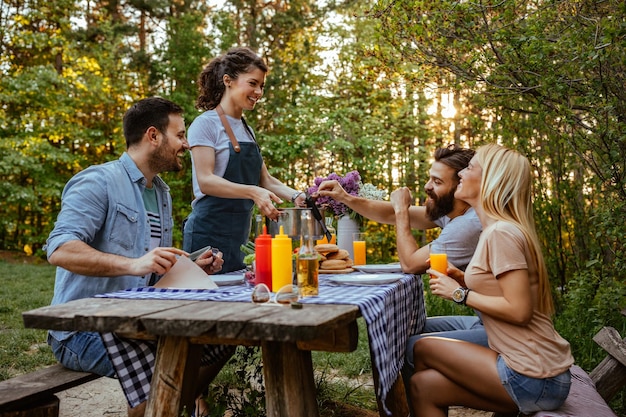 Giovane donna che serve barbecue ai suoi amici