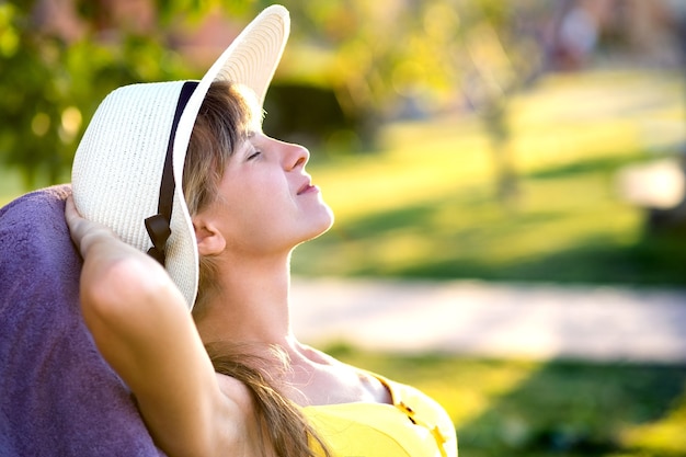 Giovane donna che si distende all'aperto sulla soleggiata giornata estiva.