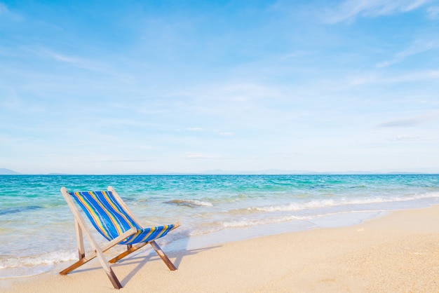 Giovane donna che si distende su una sedia su una spiaggia al giorno pieno di sole
