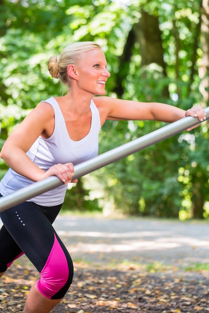 Giovane donna che si estende prima dello sport sul percorso fitness