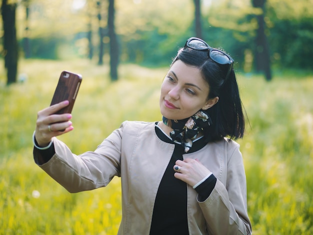 Giovane donna che si fa un selfie in piedi sul campo erboso