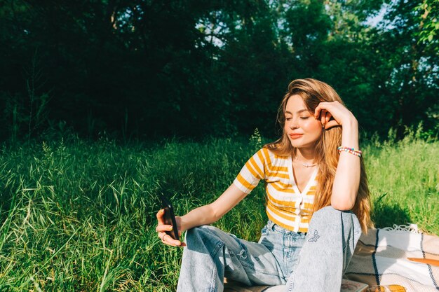 Giovane donna che si fa un selfie in un picnic all'aperto