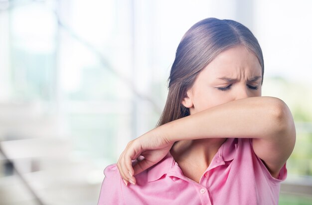 Giovane donna che si gratta il naso con il gomito sullo sfondo