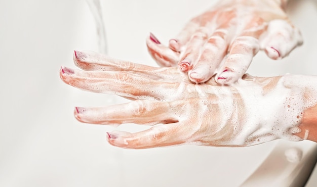 Giovane donna che si lava le mani sotto il rubinetto dell'acqua con sapone. Dettaglio sulla pelle insaponata. Concetto di igiene personale - prevenzione delle epidemie di coronavirus covid 19