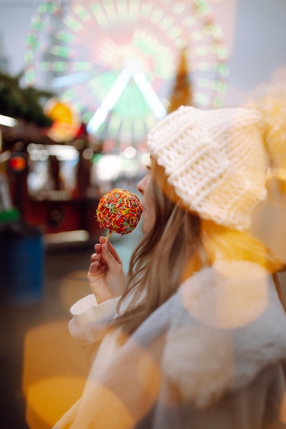 Giovane donna che si rilassa bevendo caffè nella fiera natalizia festiva. Vacanze invernali. Luci intorno.