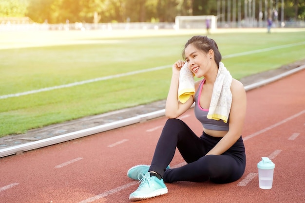 Giovane donna che si rilassa dopo l'allenamento fitness allo stadio di calcio al mattino con il chiarore del sole