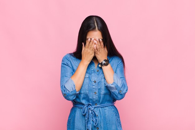 Giovane donna che si sente triste, frustrata, nervosa e depressa, coprendosi il viso con entrambe le mani, piangendo