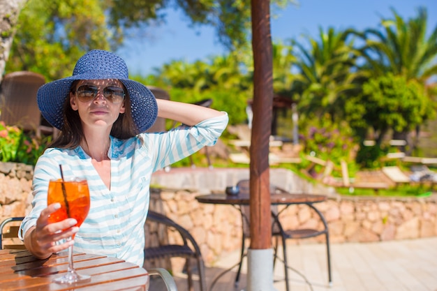 Giovane donna che si siede in caffè tropicale vicino alla piscina