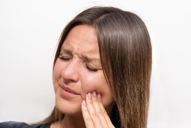 Giovane donna che si tocca la guancia a causa di un forte dolore ai denti