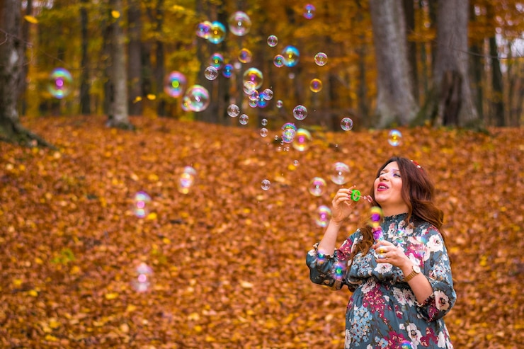 Foto giovane donna che soffia bolle nella foresta durante l'autunno
