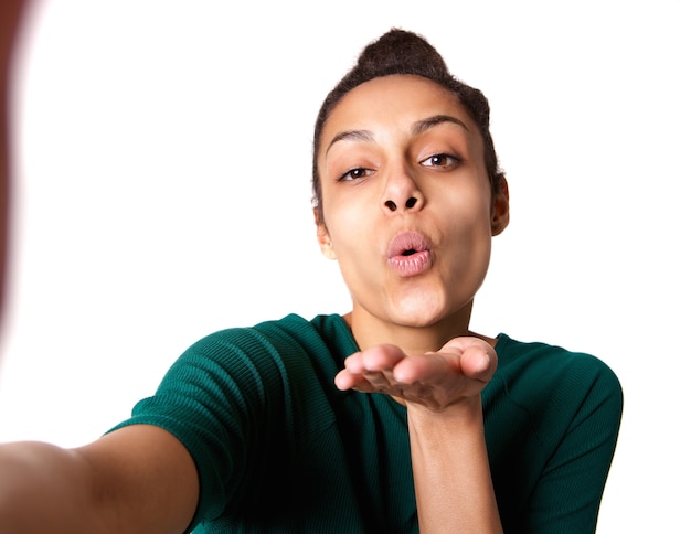 Giovane donna che soffia un bacio e prendendo selfie