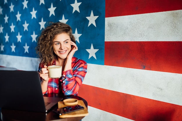 giovane donna che sogna qualcosa mentre è seduta con un net-book portatile nel moderno bar caffetteria