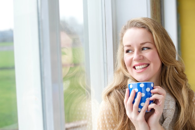 Giovane donna che sorride con la tazza di tè