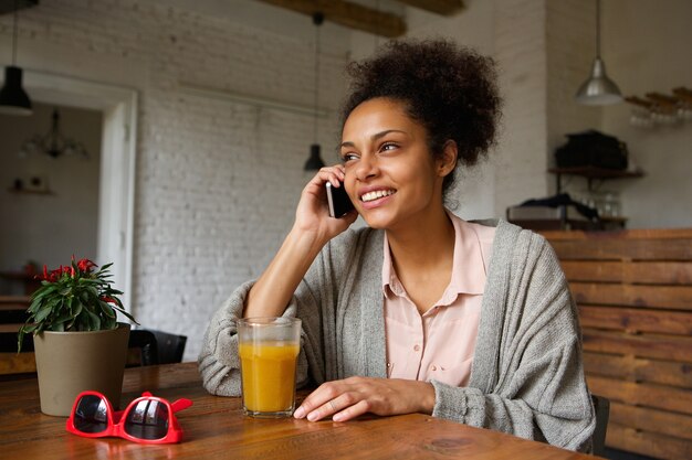 Giovane donna che sorride e che parla sul telefono cellulare