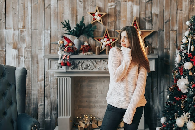 Giovane donna che sta vicino all'albero di Natale