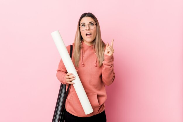 Giovane donna che studia architettura che indica parte superiore con la bocca aperta.