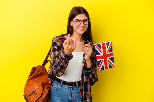 Giovane donna che studia inglese sul rosa puntando il dito su di te come se invitando ad avvicinarsi