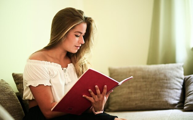 Giovane donna che studia seduto sul suo divano nel suo appartamento