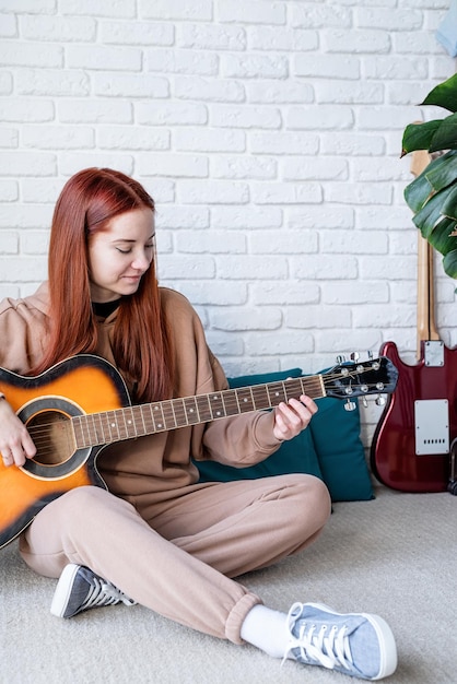 Giovane donna che suona la chitarra a casa